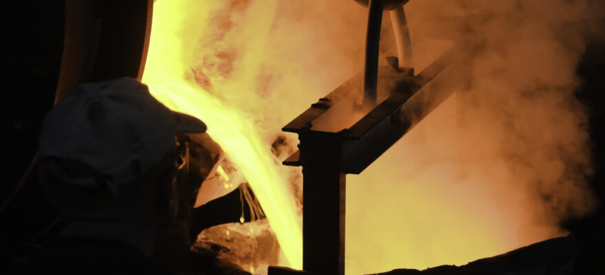 A color image of molten steel pouring at steel plant. Stock footage. Flowing metal at the foundry. Pouring of liquid metal in open hearth workshop.